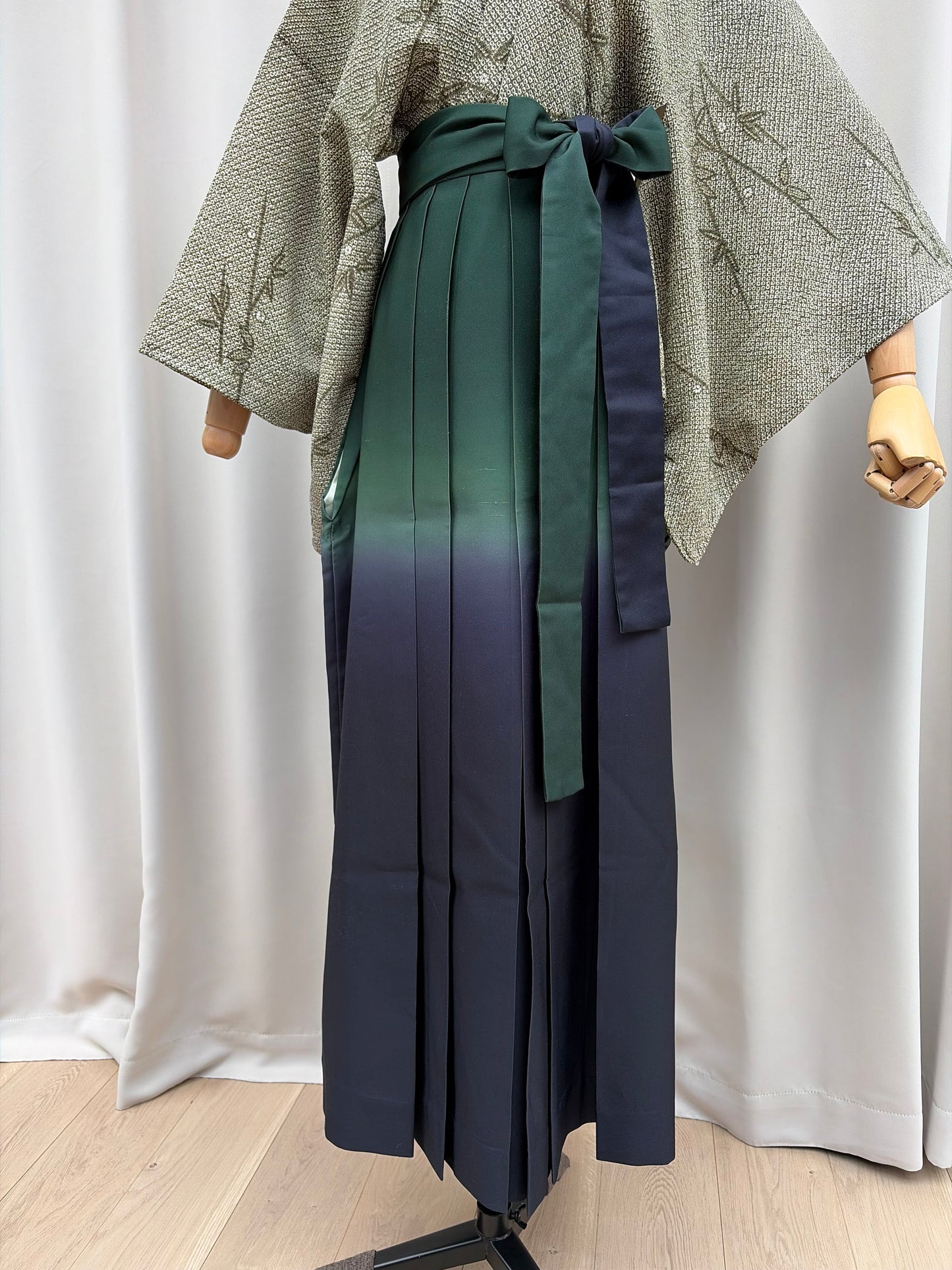 Navy Japanese hakama with green ombre pleats styled over a green kimono on a mannequin