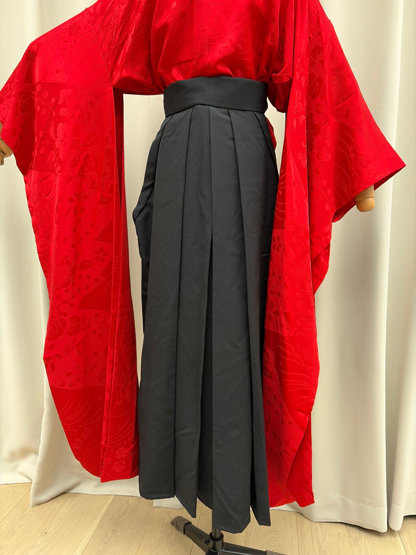 Full-length black pleated hakama styled over a red kimono