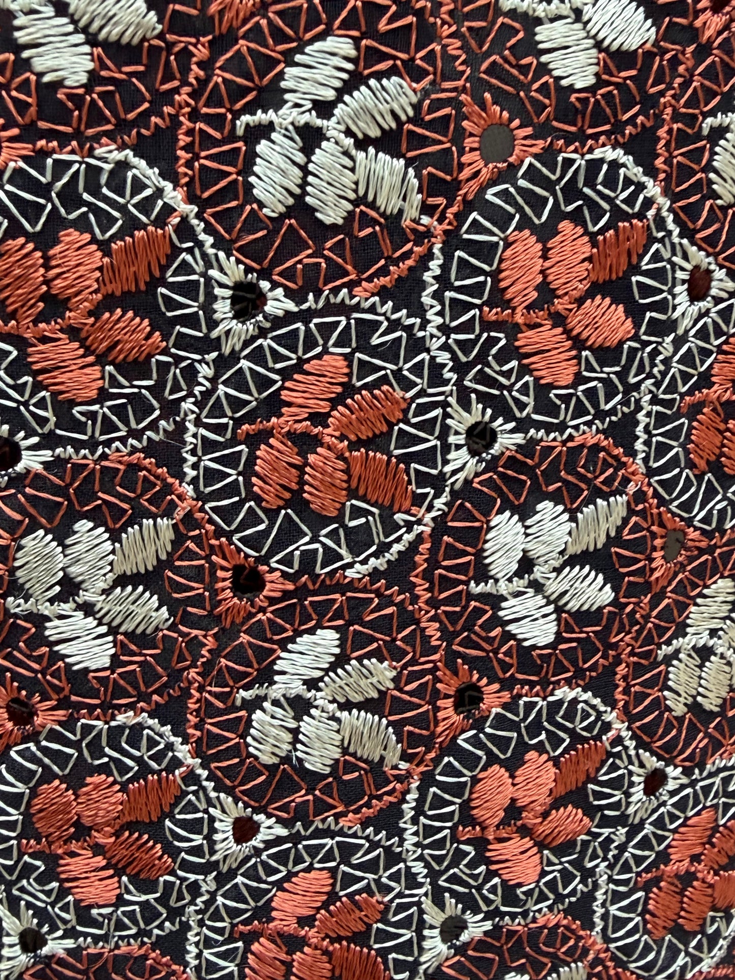 Close-up of the floral cutwork embroidery with tiny eyelet holes