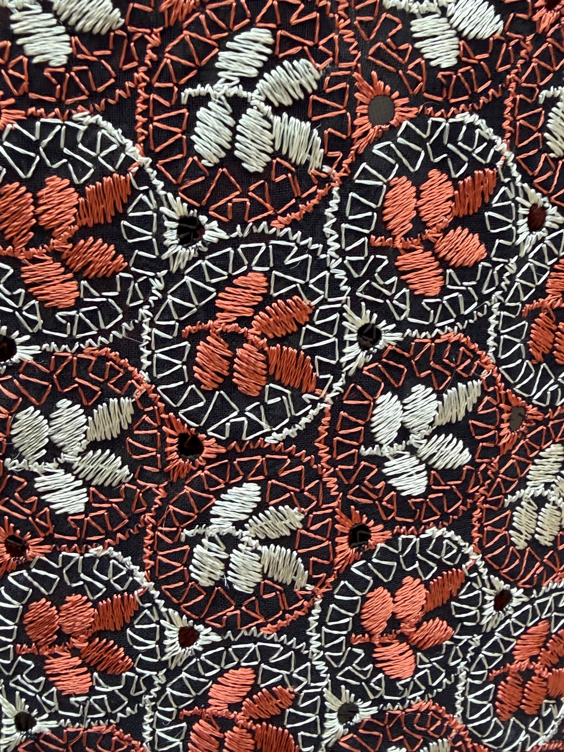 Close-up of the floral cutwork embroidery with tiny eyelet holes