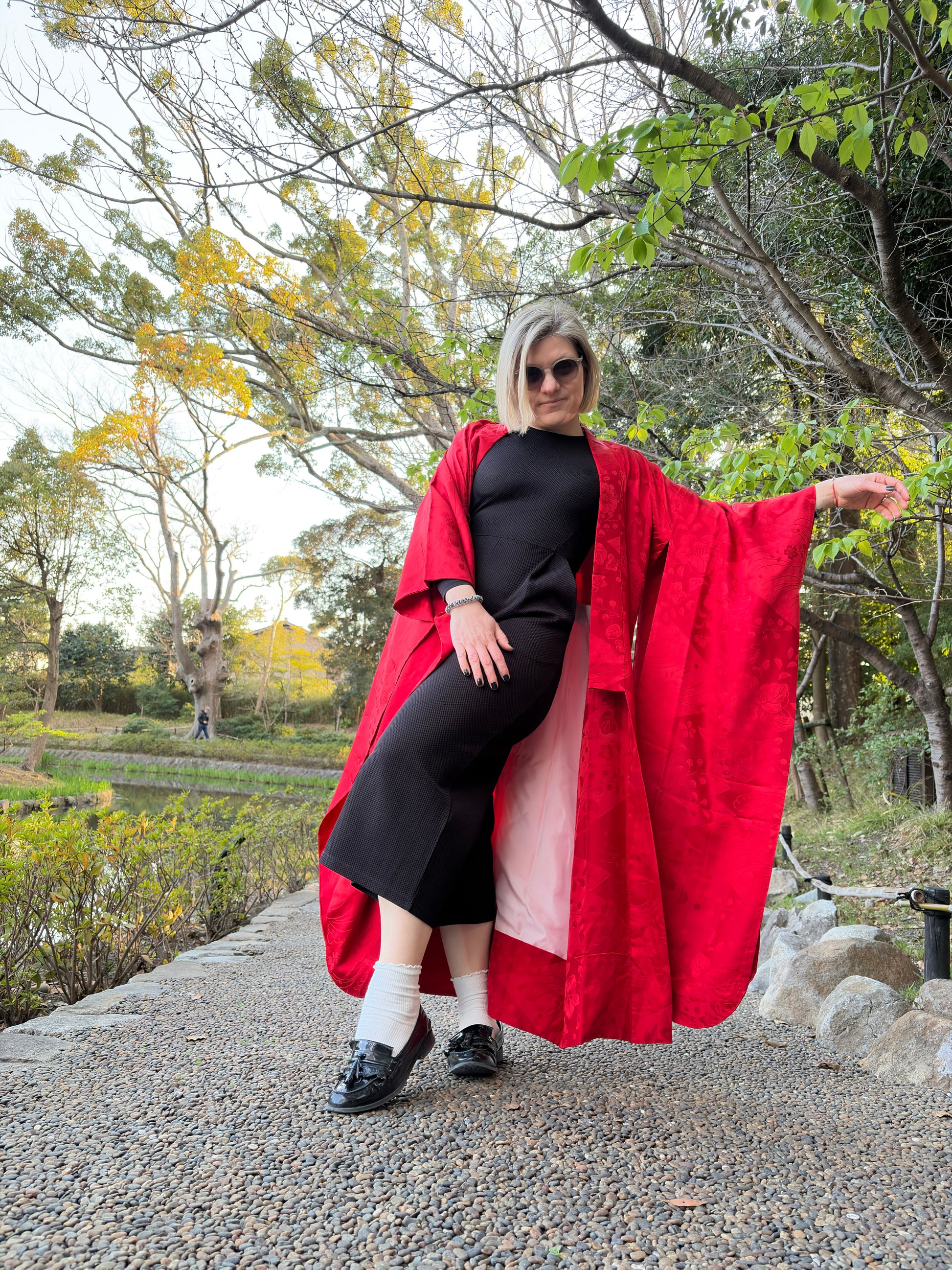 Woman wearing the vintage red nagajuban open over a black outfit in a garden