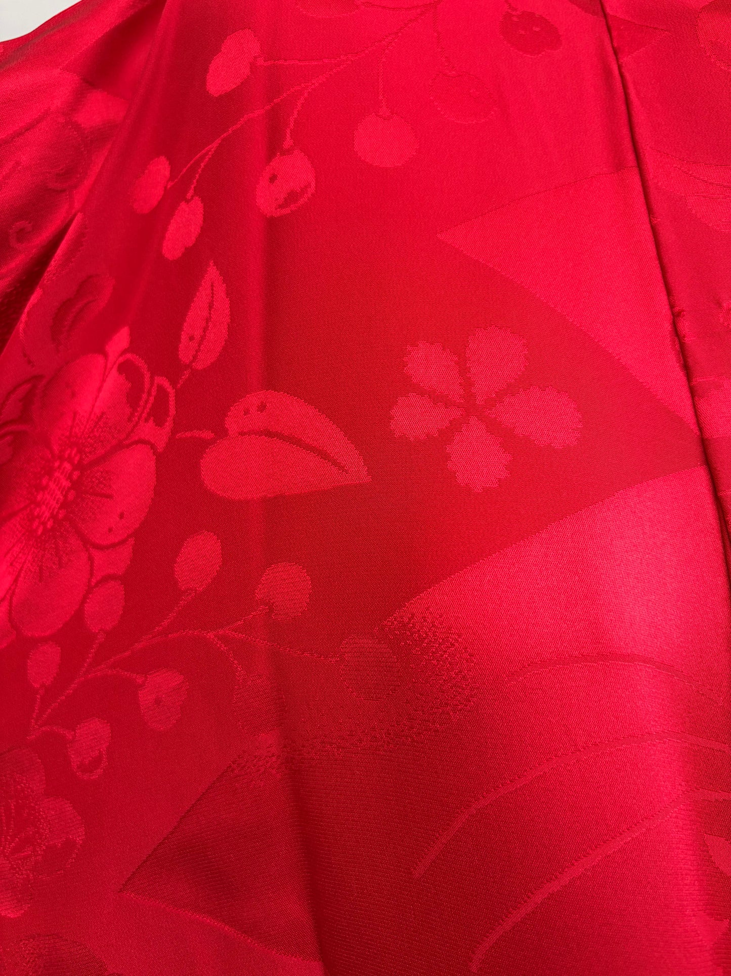 Close-up of the red nagajuban's woven cherry blossom, plum and berry pattern