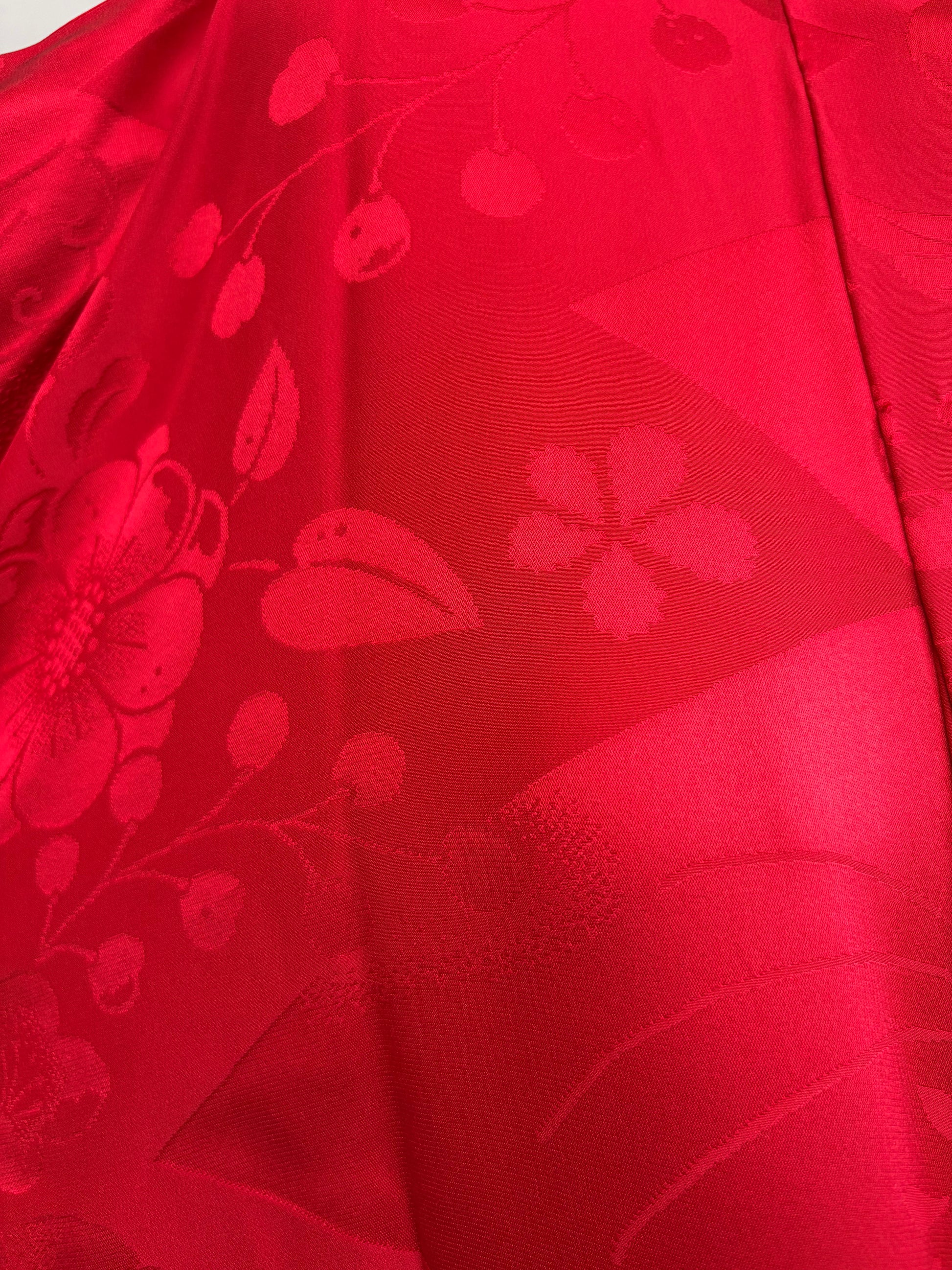 Close-up of the red nagajuban's woven cherry blossom, plum and berry pattern
