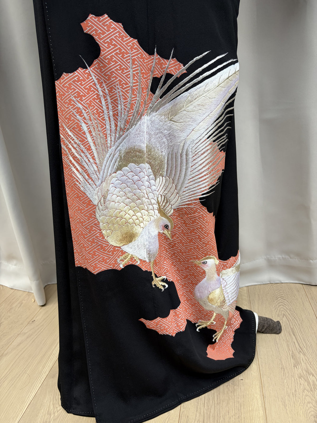 Embroidered pheasant design rising from the hem of the black kimono