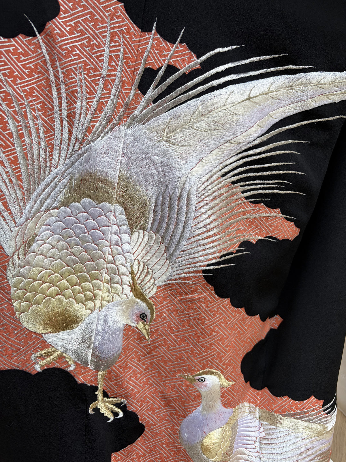 A pair of embroidered pheasants in silver and gold on the black kimono