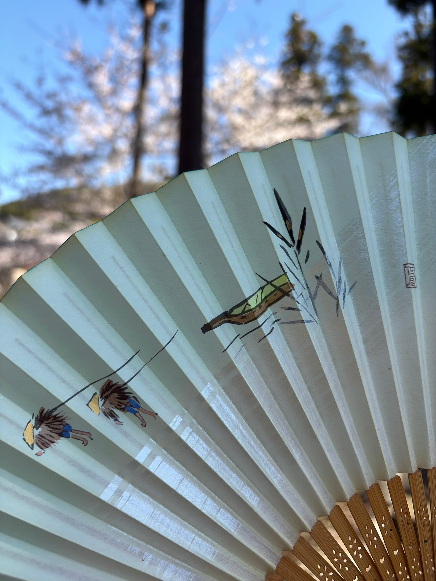 Close-up of the painted bamboo, figures and artist's seal on the fan
