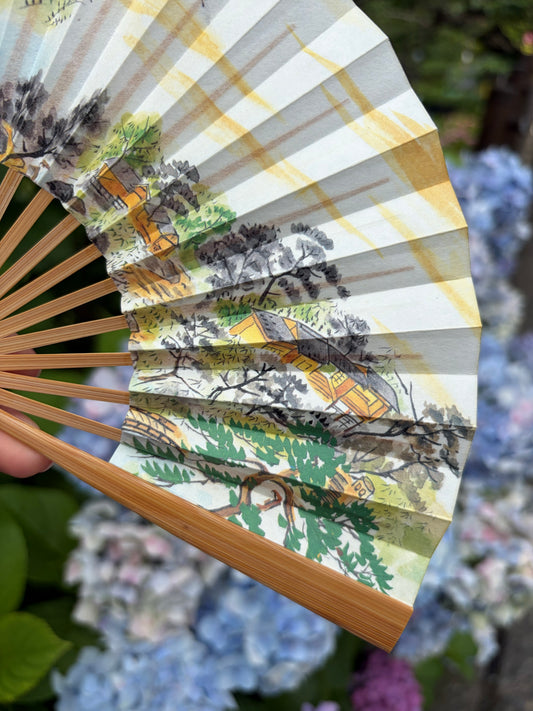 Close-up of the painted village and pine trees on the paper fan